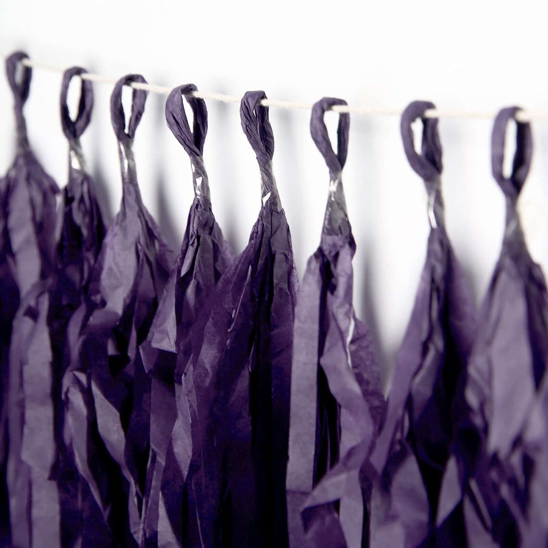 Purple tissue paper tassels hanging decoratively on a string.