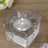 Silver candle in a clear glass holder on a wooden surface.