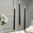 Three elegant black taper candles in gold holders on a stylish table setting.