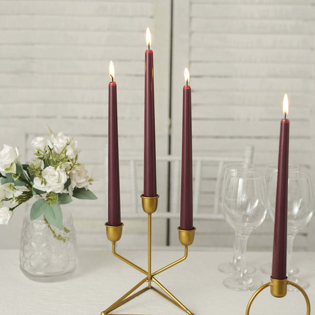 Elegant gold candle holder with burgundy candles and a floral centerpiece.