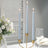 Elegant blue taper candles in a gold candle holder with white flowers and glassware.