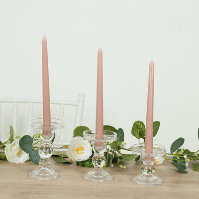 Three elegant candle holders with pink candles and greenery decor.