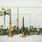 Elegant candle holders with colorful candles and greenery on a table setting.