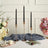 Elegant black twisted candles in gold holders on a decorative table setting.