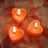 Heart-shaped candles glowing on rose petal backdrop.