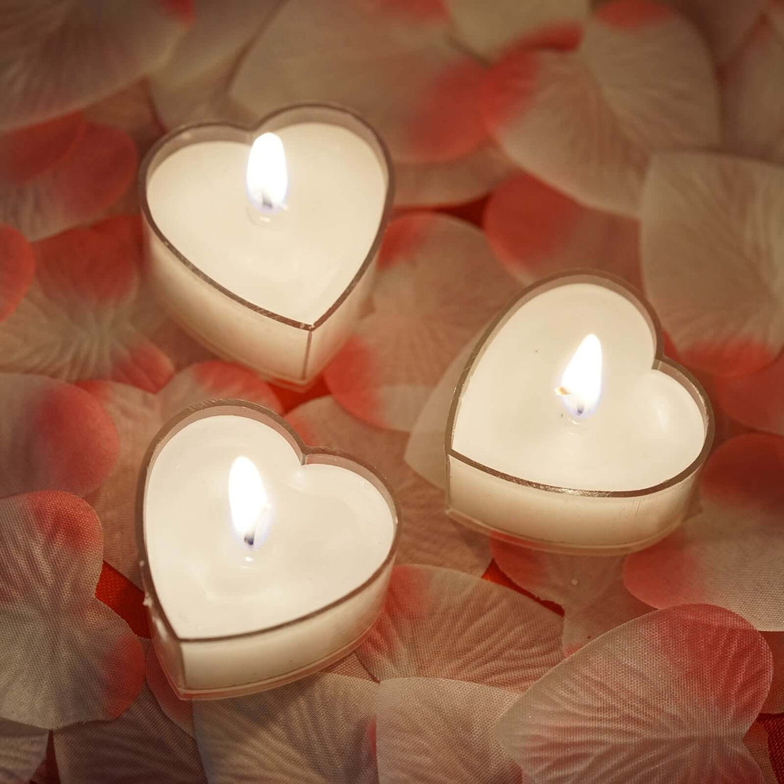 Heart-shaped candles surrounded by rose petals.