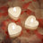 Heart-shaped candles surrounded by rose petals.