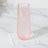 Pink glass with ice on a napkin against a marble surface.