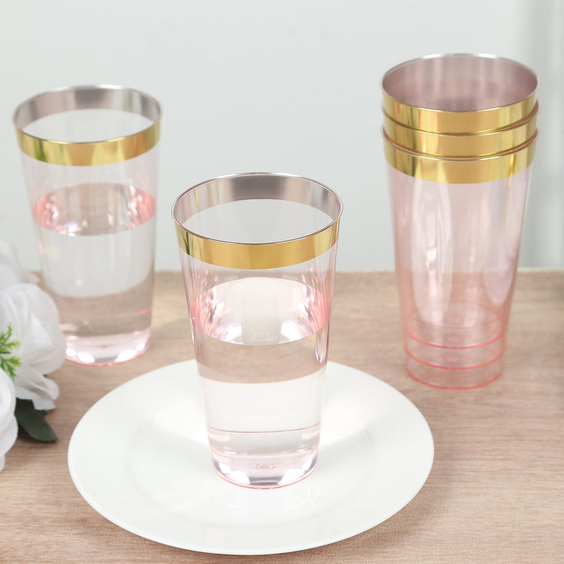 Set of stylish pink and gold rimmed drinking glasses on a plate.
