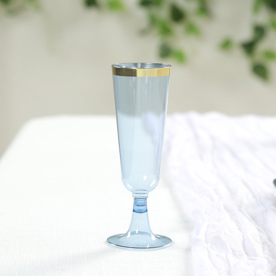 Blue champagne flute with gold rim on a soft background.