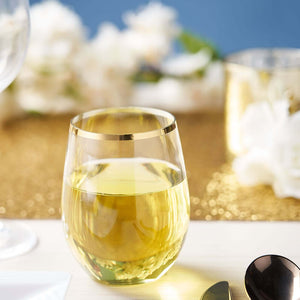 Elegant glass with golden rim filled with yellow beverage on a tabletop.