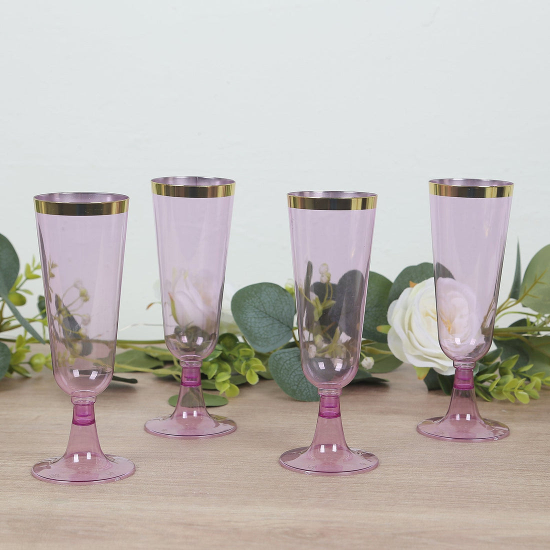 Set of four elegant pink champagne flutes with gold rims.