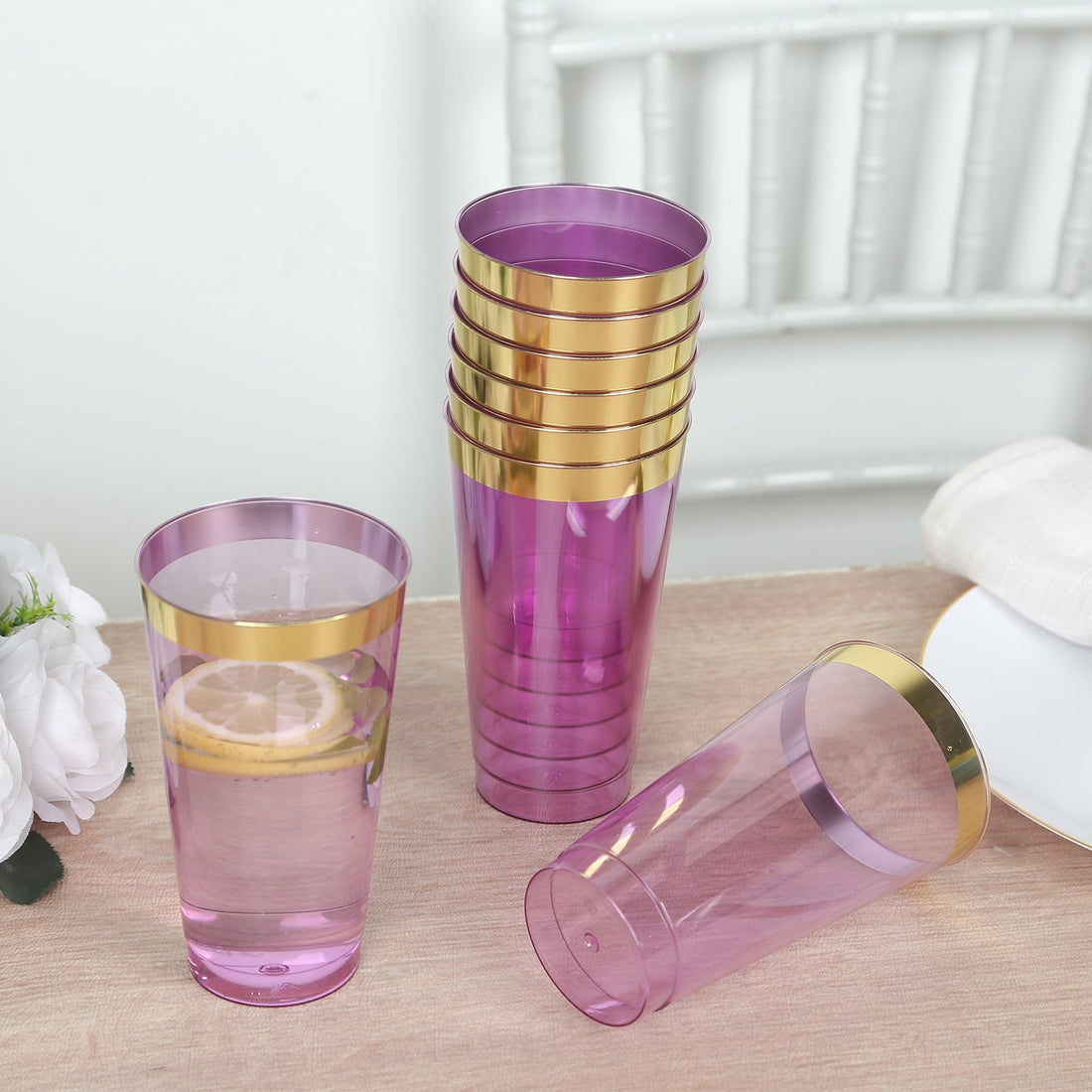 Set of purple plastic cups with gold rims on a wooden table.