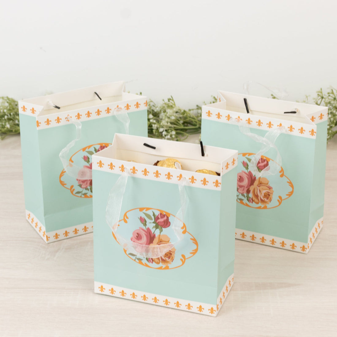 Colorful floral gift bags on a light wooden surface.
