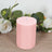 Pink pillar candle surrounded by greenery and white flowers.