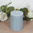 Blue pillar candle surrounded by greenery and white roses.