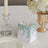 Decorative gift bag with green leaf design on a dining table setting.