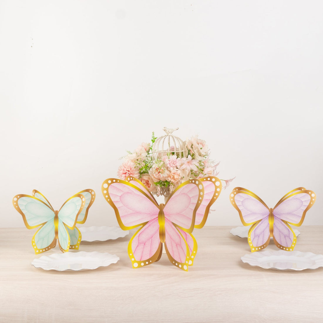 Colorful butterfly decorations on white plates with a floral centerpiece.