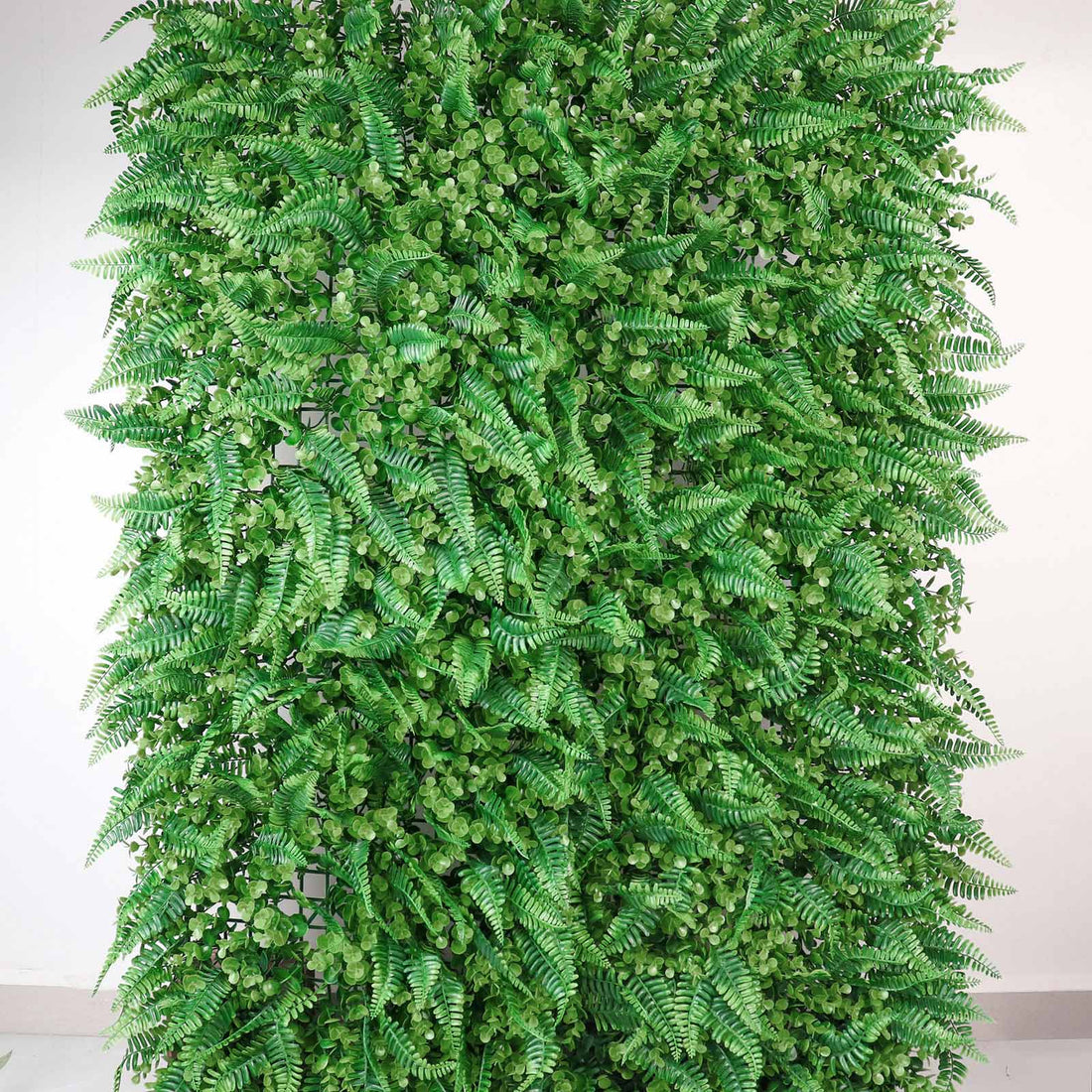 Artificial green fern wall panel for decor and landscaping.