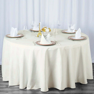 Elegant round dining table set with fine china and glassware, complete with decorative centerpiece.