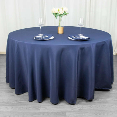Round navy tablecloth on a dining table set with plates and glasses.