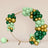 Green and gold balloon arch on a plain backdrop