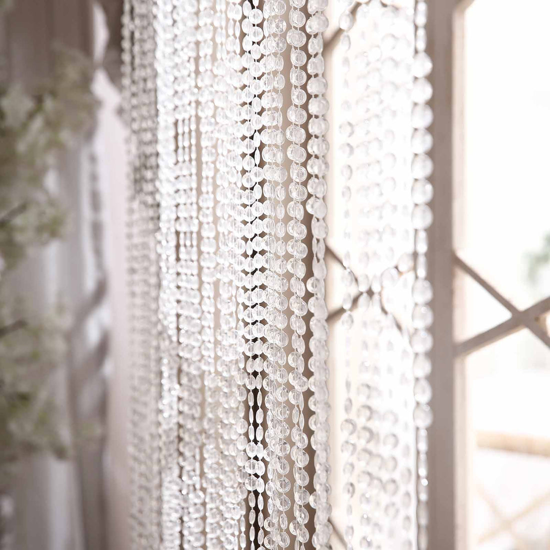 Crystal beaded curtain hanging near a window, creating a sparkling effect.