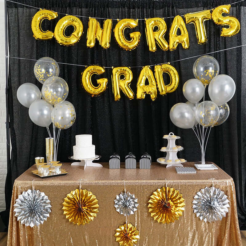 Gold and silver graduation party decorations with balloons, cake, and table setup.
