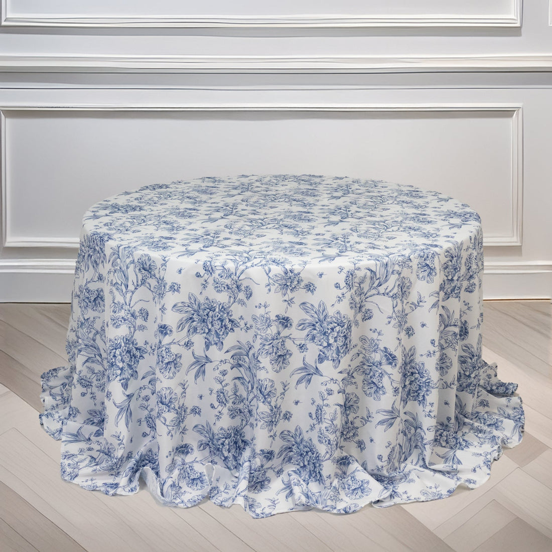 Round floral tablecloth in blue and white on a light wooden surface.