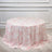 Round floral tablecloth in soft pink and white on a light wooden floor.
