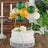 Birthday cake adorned with balloons and floral accents.