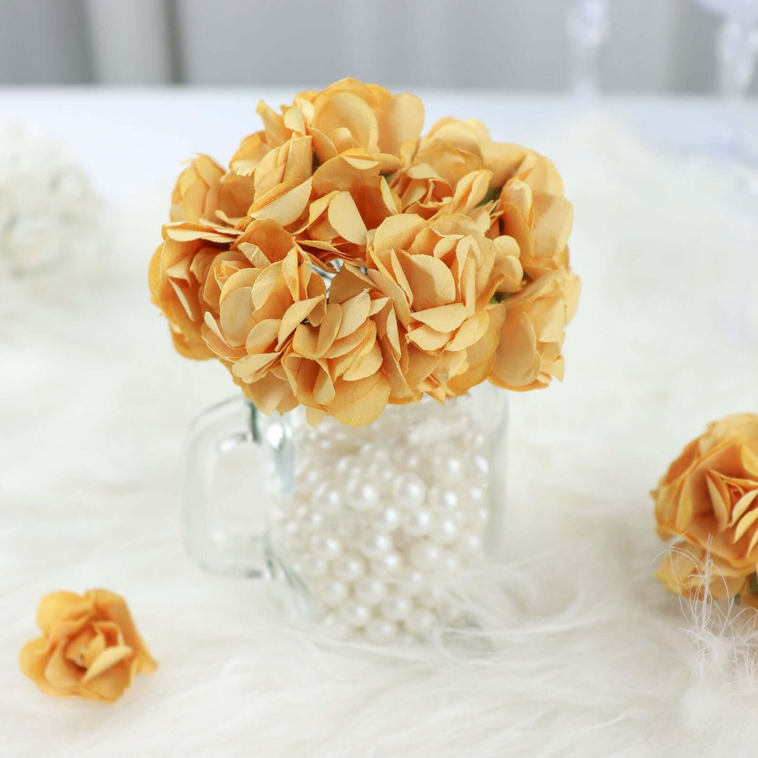Yellow flower arrangement in a glass mug with pearls
