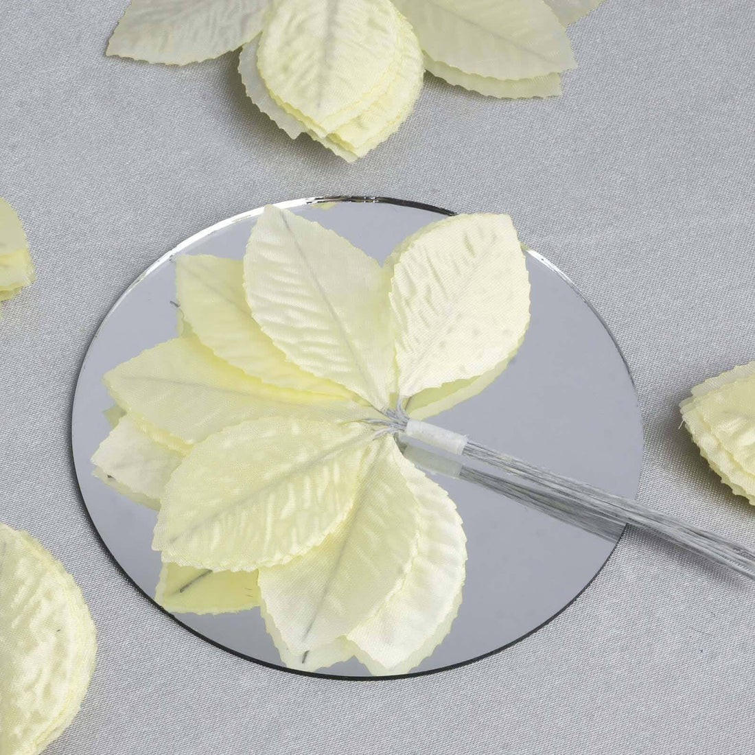 Yellow fabric leaves on a mirrored surface.
