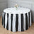 Round table with black and white striped tablecloth and floral centerpiece.