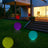 Colorful outdoor LED garden balls illuminating a backyard at night.