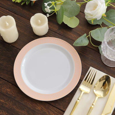 Elegant white plate with peach patterned rim, surrounded by candles and greenery.