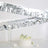 Decorative silver streamers with a white cake and flowers on a table.