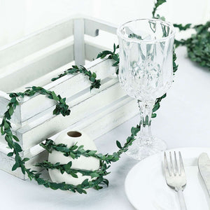 Decorative table setting with greenery, glassware, and white crate.
