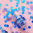 Colorful confetti scattered around a glass on a pink background.