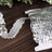 Silver sequin trim on a wooden surface with greenery in the background.
