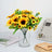 Artificial sunflower bouquet in a glass vase on a table.