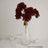 Red faux flowers in a clear glass vase with a gold accent.