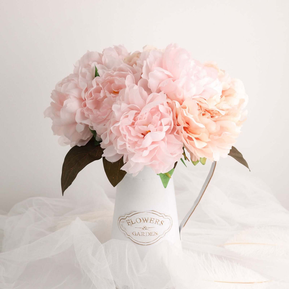 Pink peony flowers in a white pitcher vase.