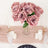 Bouquet of pink roses in a glass vase on a table with candles and crystal glasses.