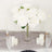White roses in a glass vase with candles on a table setting.