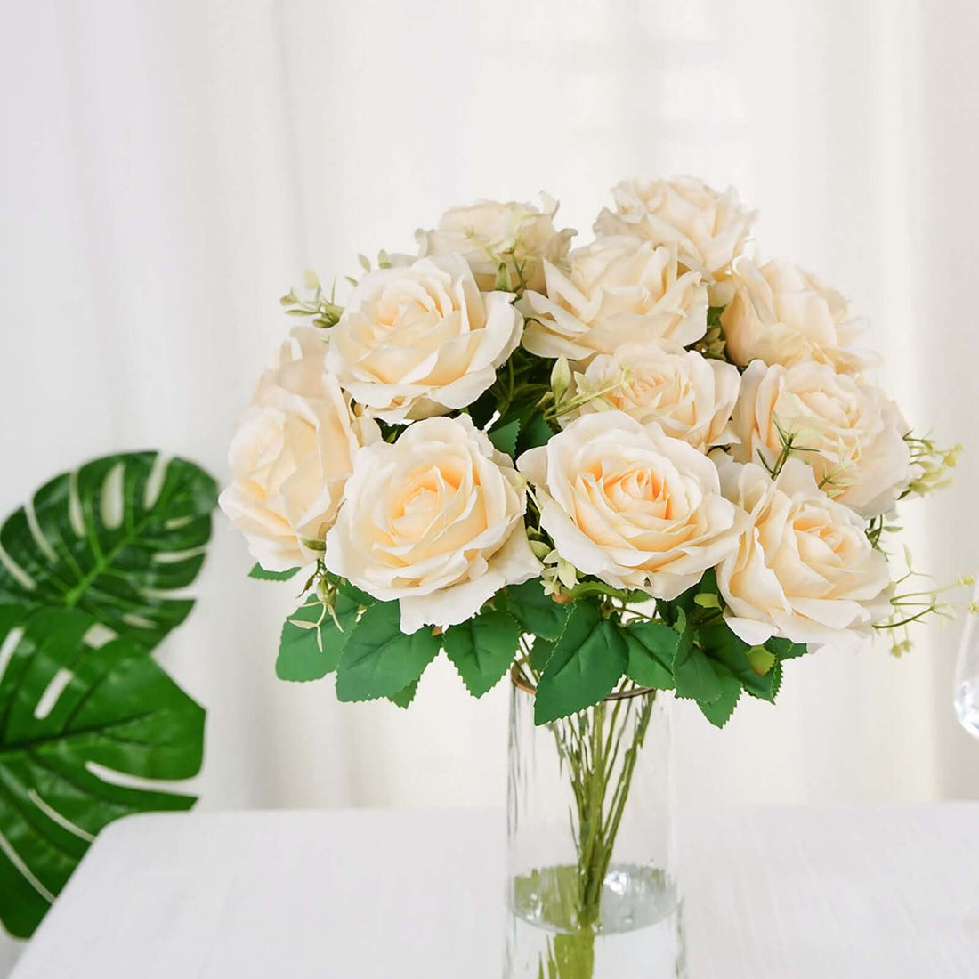 Bouquet of cream artificial roses in a clear glass vase.