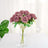 Bouquet of lavender roses in a clear vase on a white table.
