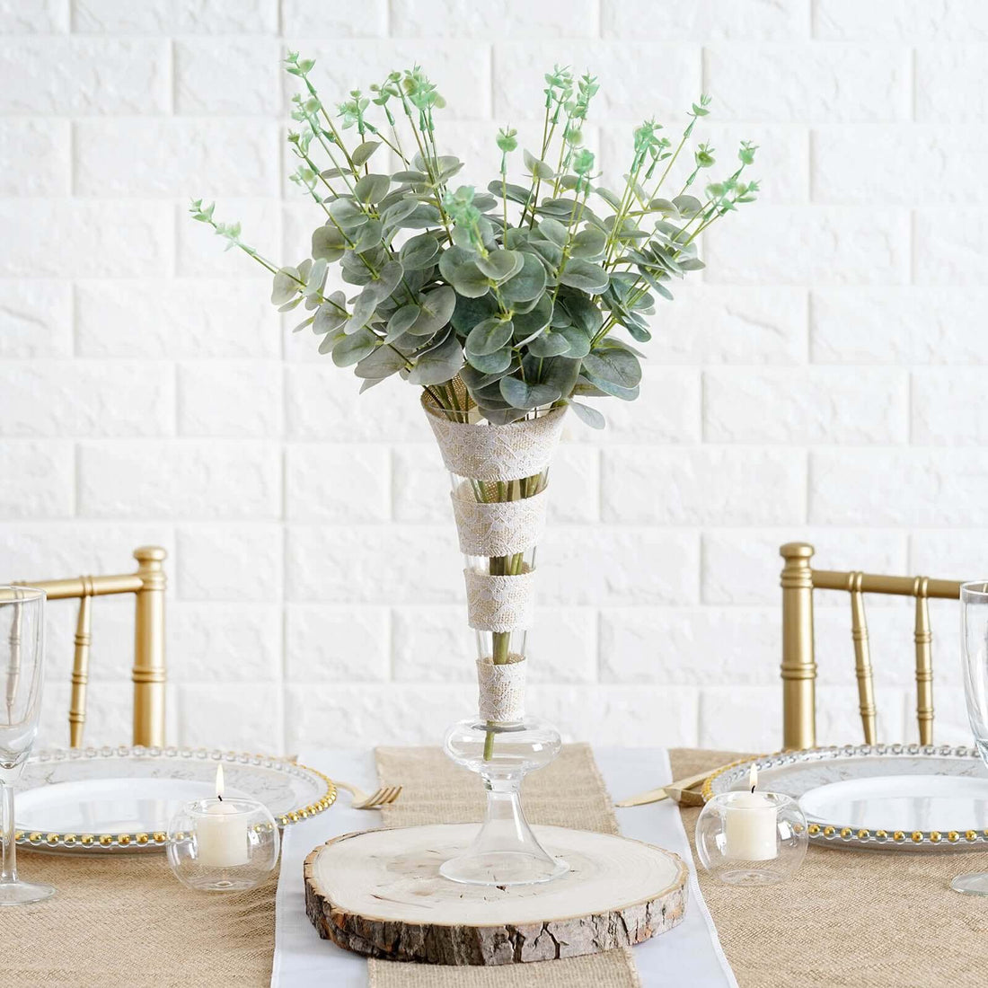 Elegant faux succulent arrangement in a glass vase on a rustic table setting.