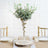 Elegant faux succulent arrangement in a glass vase on a rustic table setting.