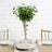 Elegant greenery centerpiece in a glass vase on a rustic wooden table.